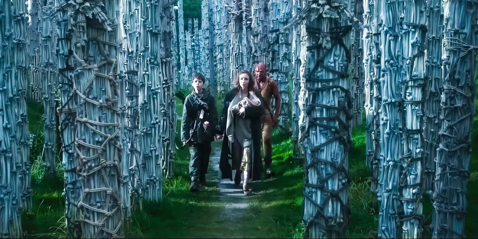 Isla (Jodie Comer), Dr. Kelson (Ralph Fiennes), and Spike (Alfie Williams) walk through the Bone Temple in 28 Years Later