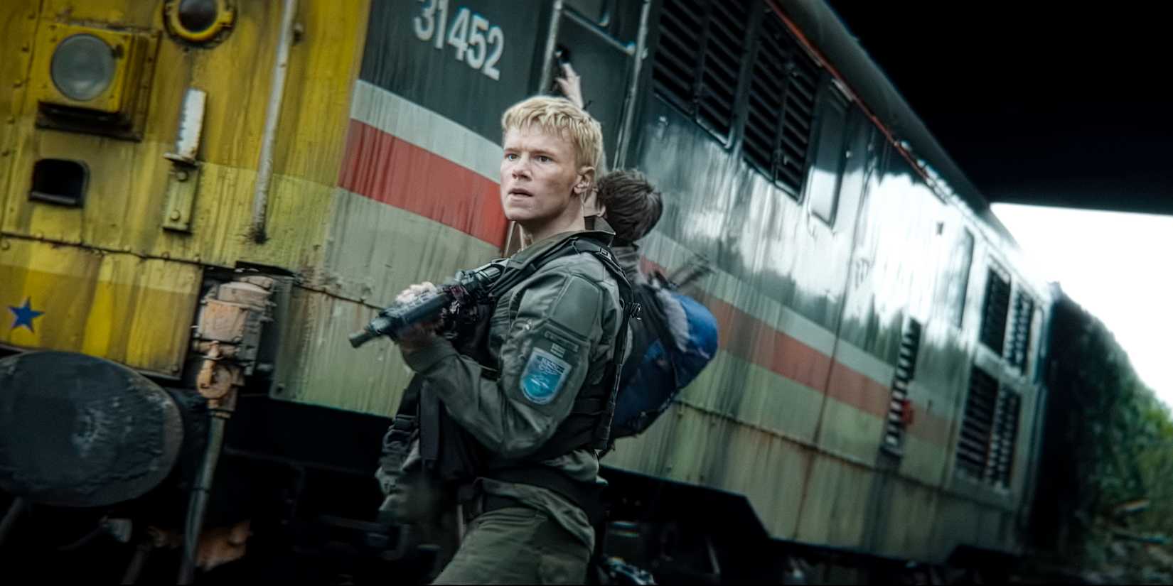 Edvin Ryding as Erik Sundqvist looking nervous outside a train in 28 Years Later