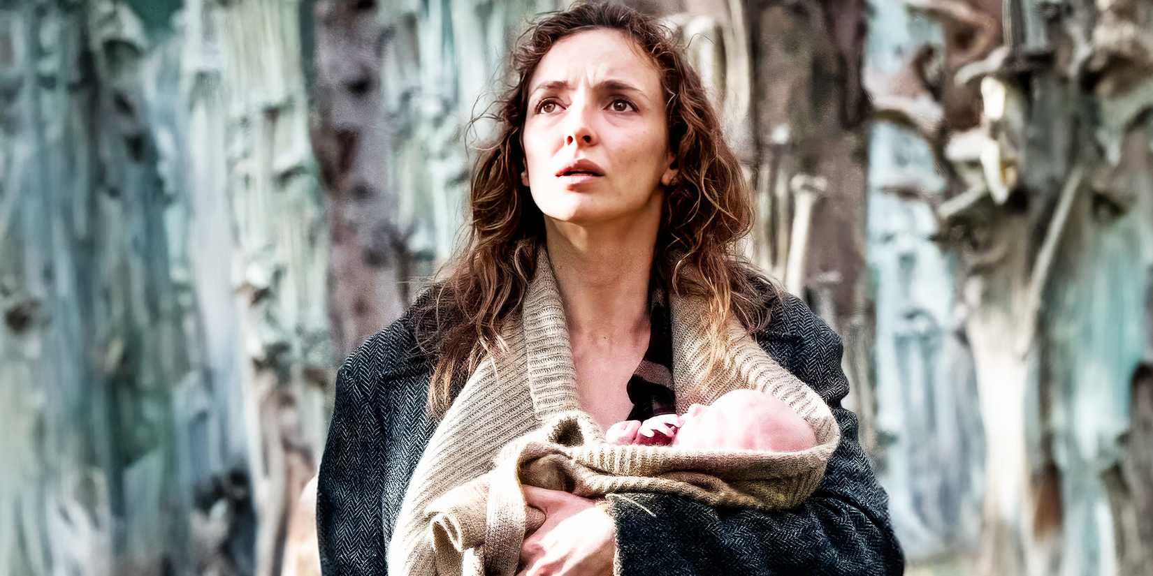 Jodie Comer as Isla looking afraid while holding a baby in 28 Years Later