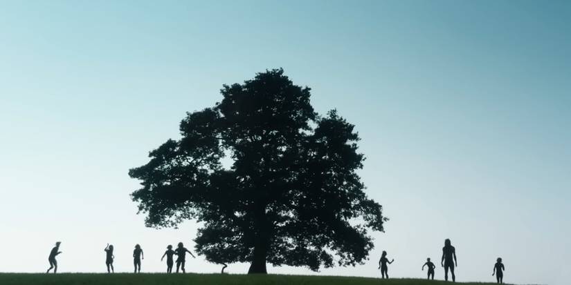 A group of Infected silhouetted on a hilltop by a tree in 28 Years Later
