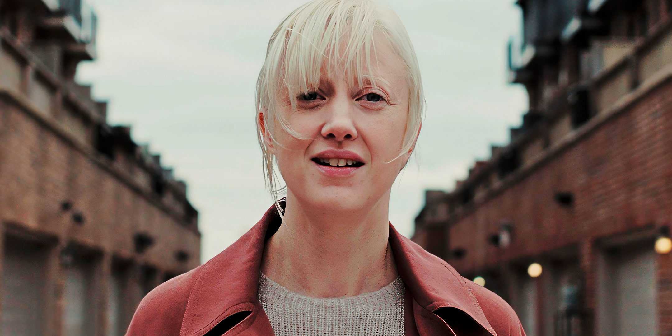 a-woman-in-a-red-coat-stands-between-two-buildings-in-possessor 10 Underrated Sci-Fi Thriller Movies Scarier Than Horror
