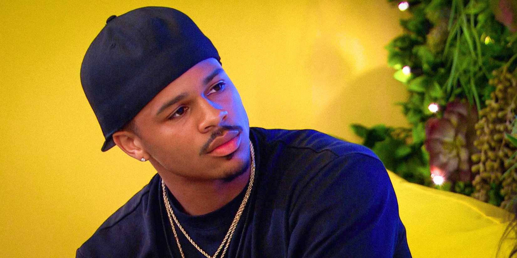 Ace Greene из "Love Island USA" с нейтральным выражением лица и желким фоном