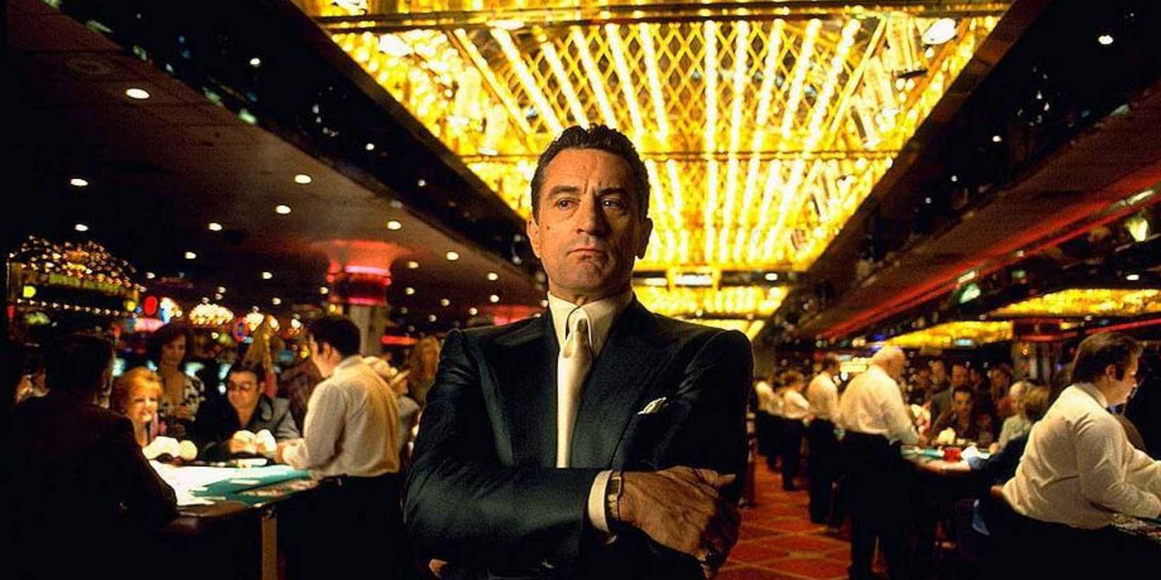 Sam stands on the casino floor with his arms crossed in Casino