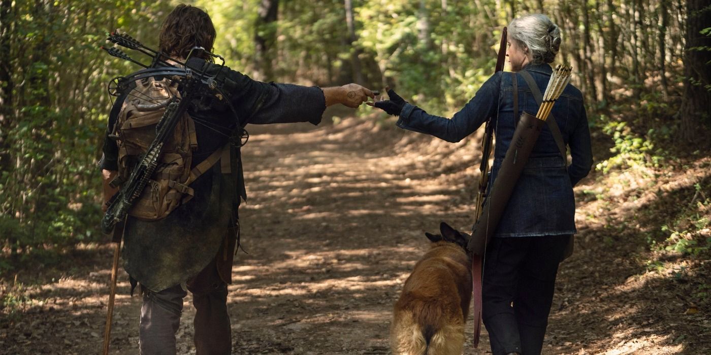 Daryl hands Carol something as they walk away from the camera with Dog in the Walking Dead