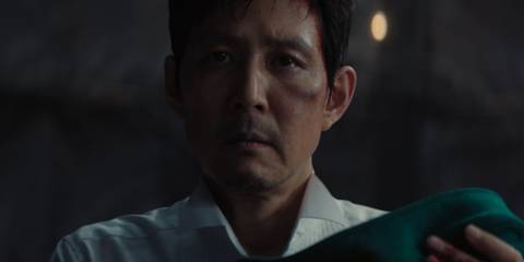 Gi-hun holding Player 222's baby and looking scared in Squid Game season 3, episode 6