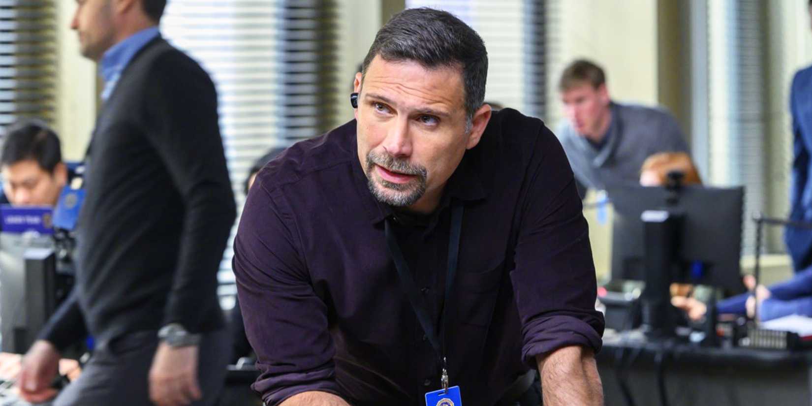 Jubal stands in the FBI headquarters with his earpiece in giving and receiving info about a case