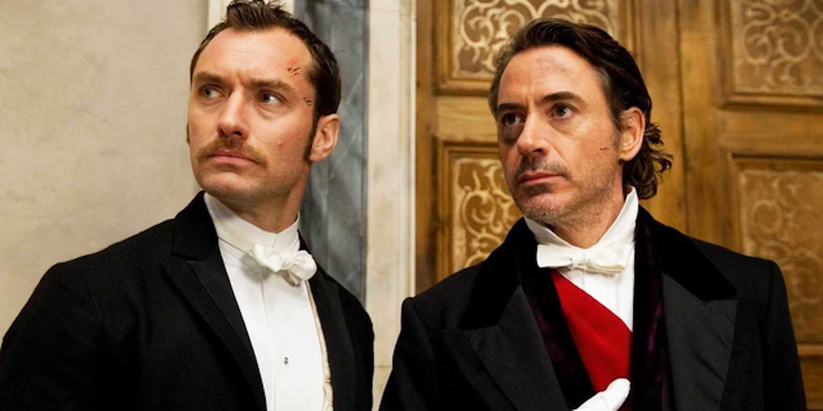 Jude Law's Watson and Robert Downey Jr's Sherlock stand outside a door in Sherlock Holmes 2009