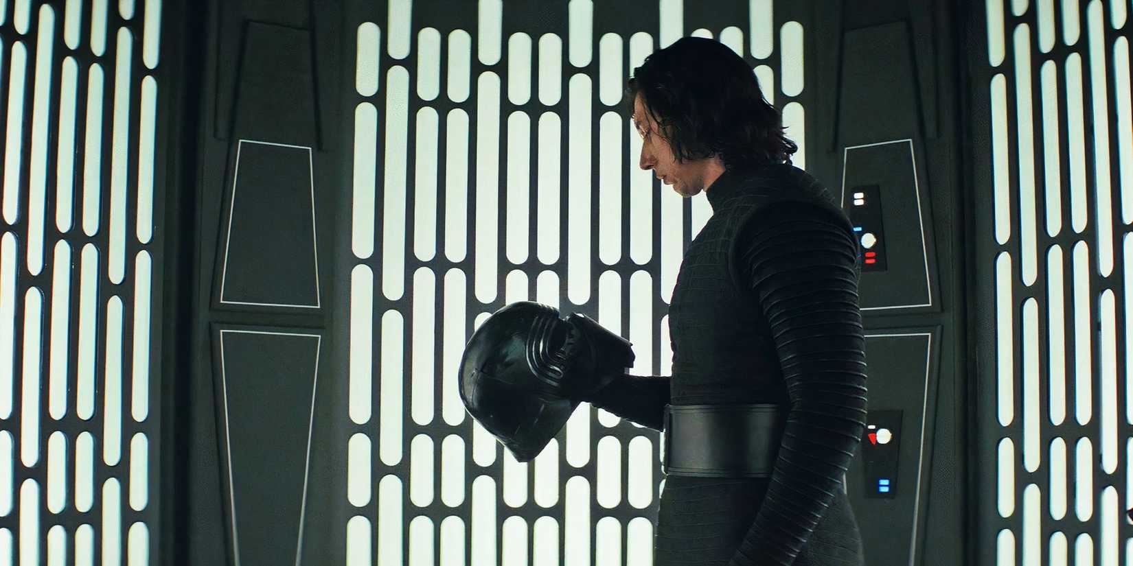 Kylo Ren holds his helmet inside an elevator and looks at it.