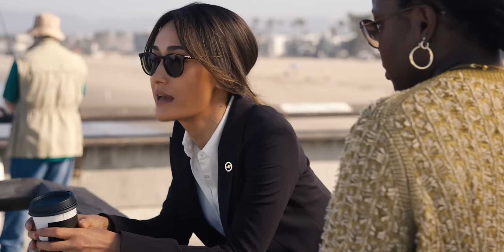 Maggie Q's Renée holding a coffee cop and leaning over a railing while talking to Courtney Taylor's Samira Parker in Ballard
