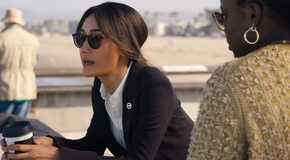 Maggie Q's Renée holding a coffee cop and leaning over a railing while talking to Courtney Taylor's Samira Parker in Ballard