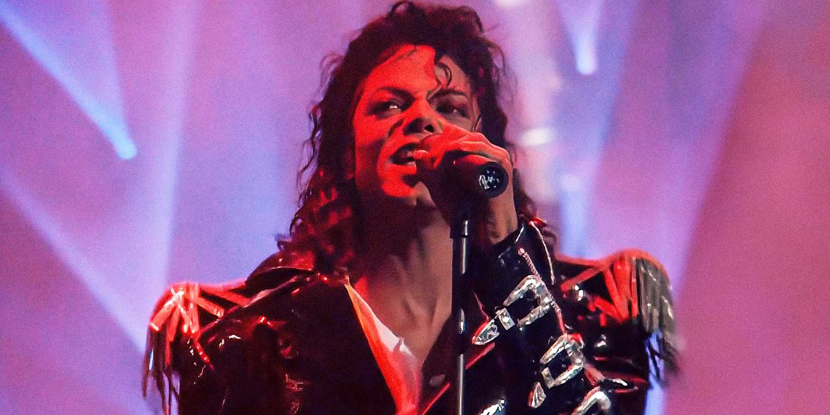 Майкл Джексон в черной кожаной куртке поет в микрофон в своем музыкальном видео 1988 года "Come Together".