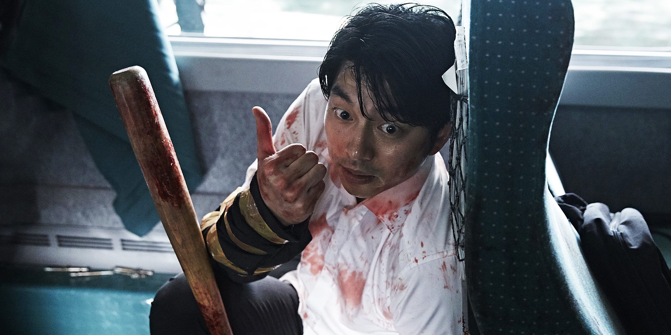 Gong Yoo hiding behind a chair holding a bat in Train to Busan