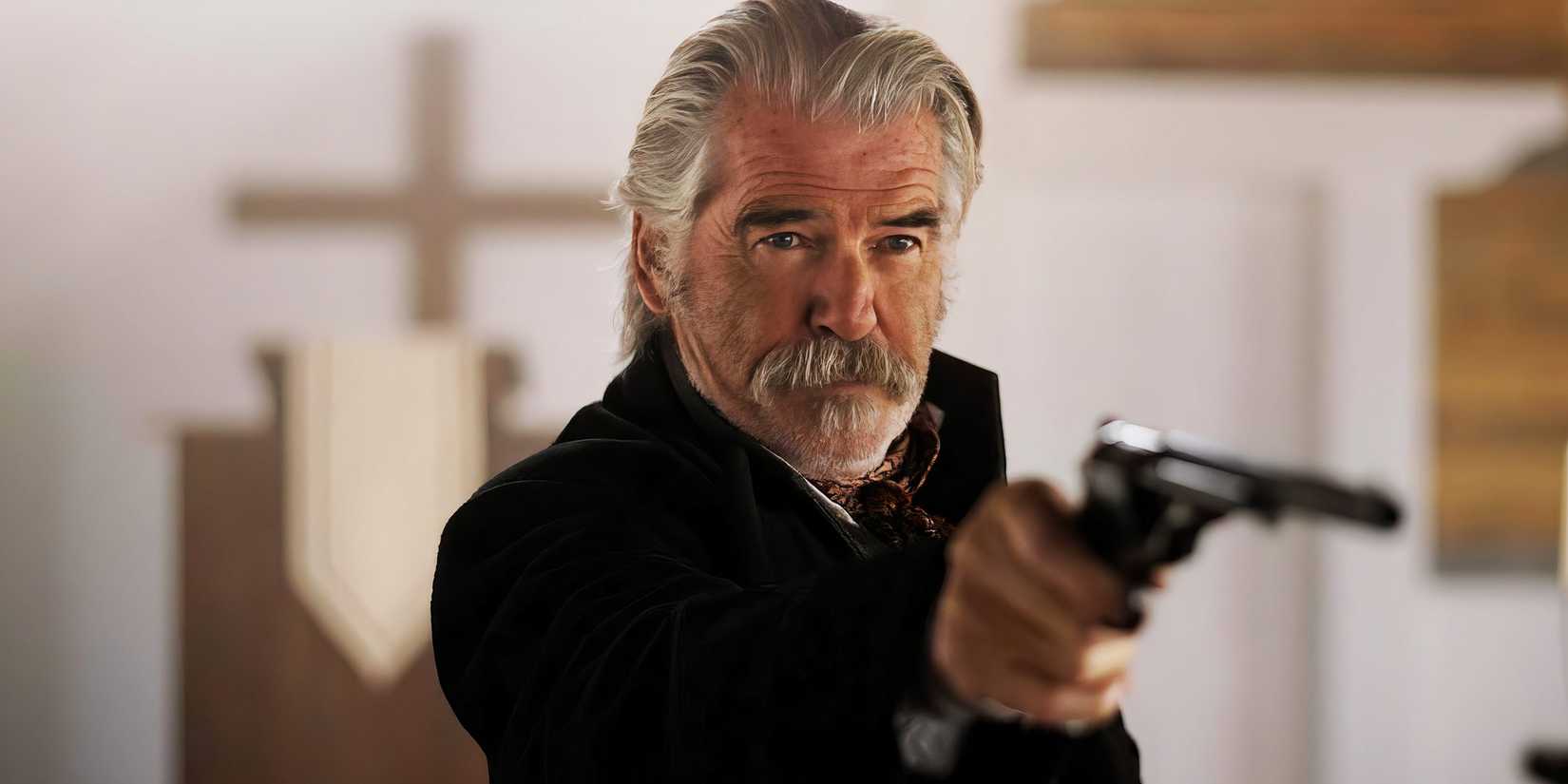 Pierce Brosnan pointing a pistol as Sheriff Gabriel Dove in The Unholy Trinity