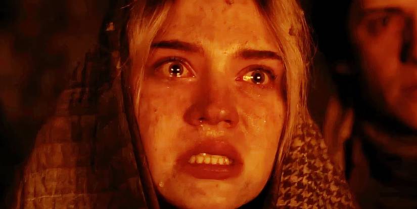 Teen Natalie (Sophie Thatcher) crying and looking shocked as she watches the cabin burn in the Yellowjackets season 2 finale