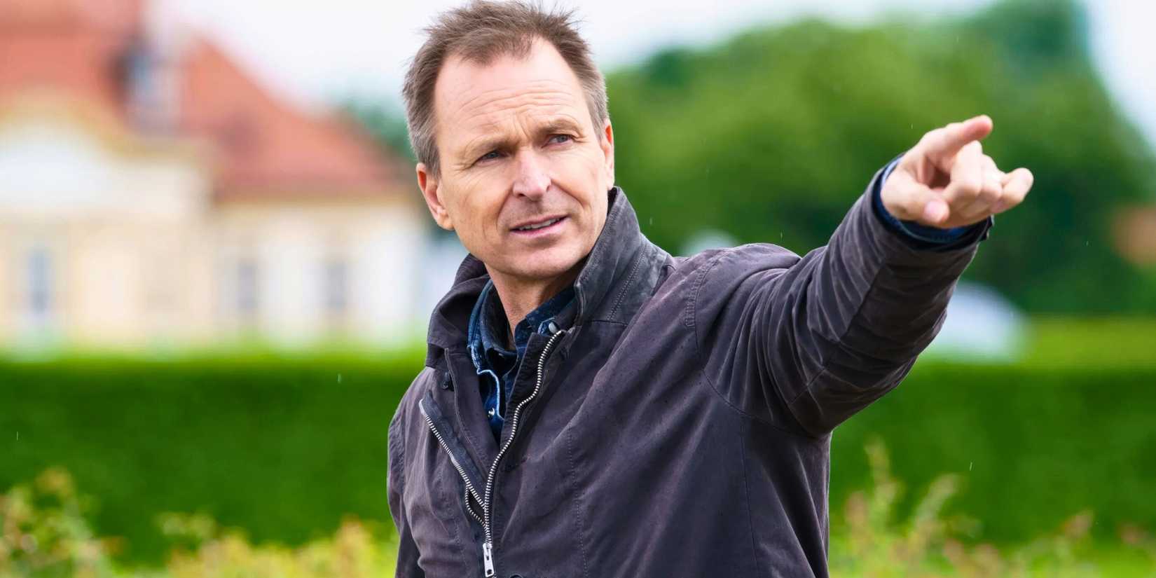 The Amazing Race host Phil Keoghan with his finger pointed in a direction