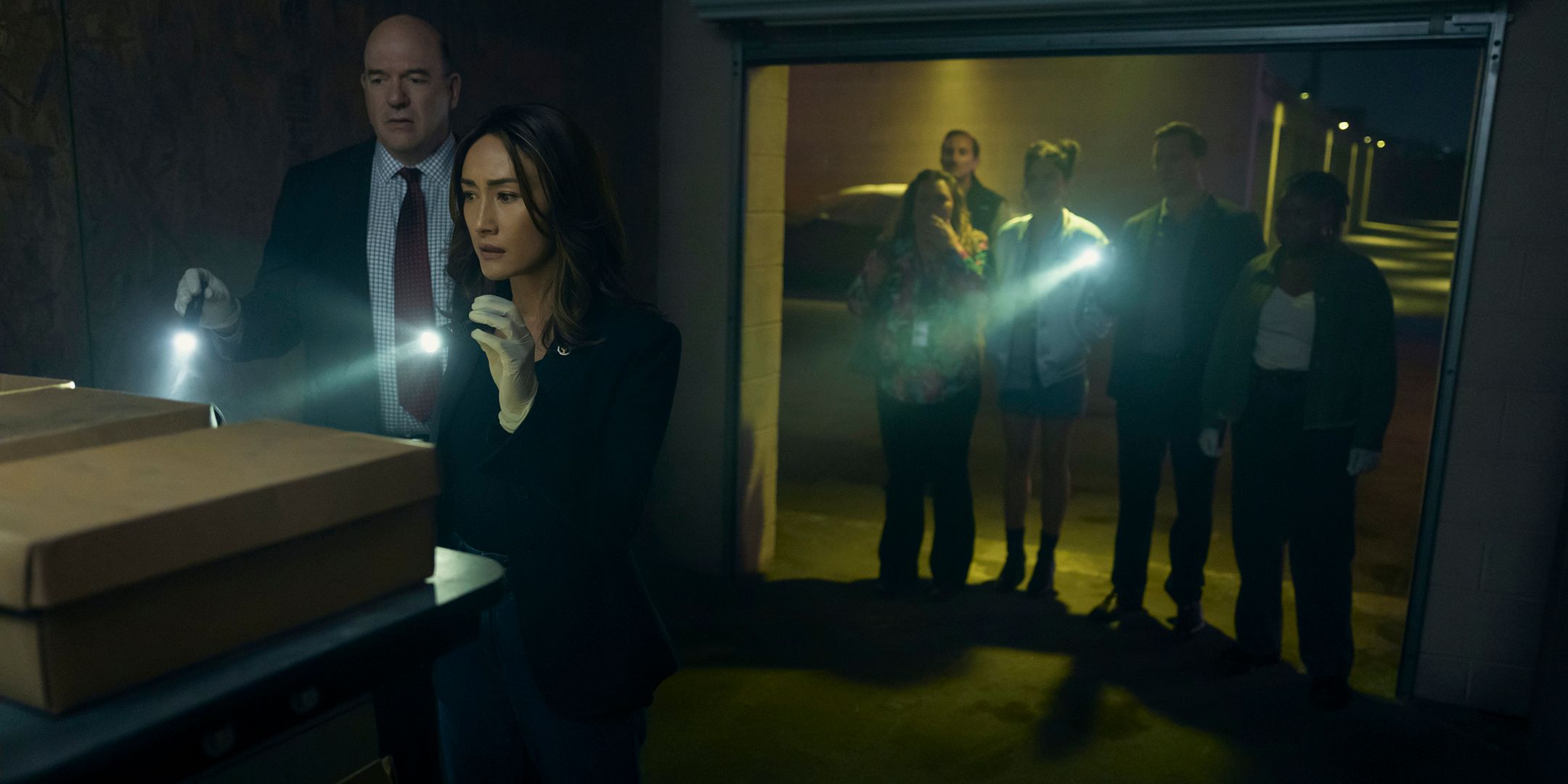 The group holding flashlights and investigating boxes in a storage unit in Ballard