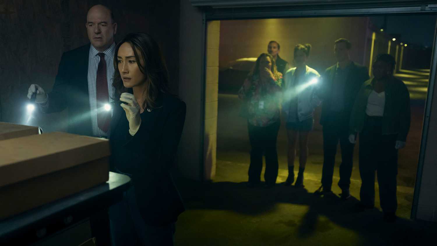 The group holding flashlights and investigating boxes in a storage unit in Ballard