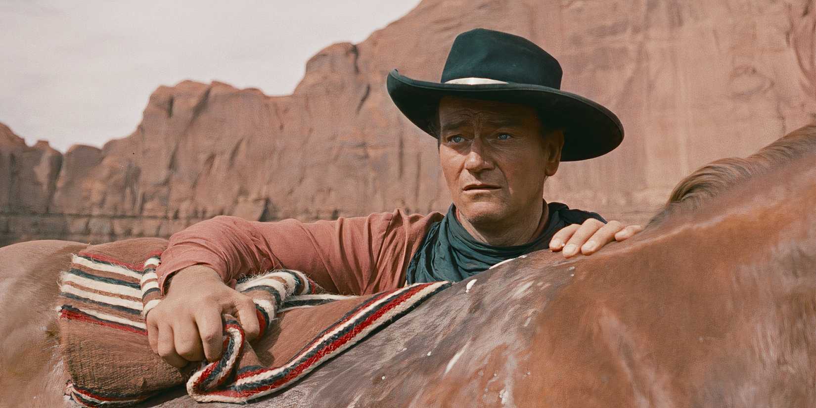John Wayne looks out dramatically while saddling his horse in The Searchers