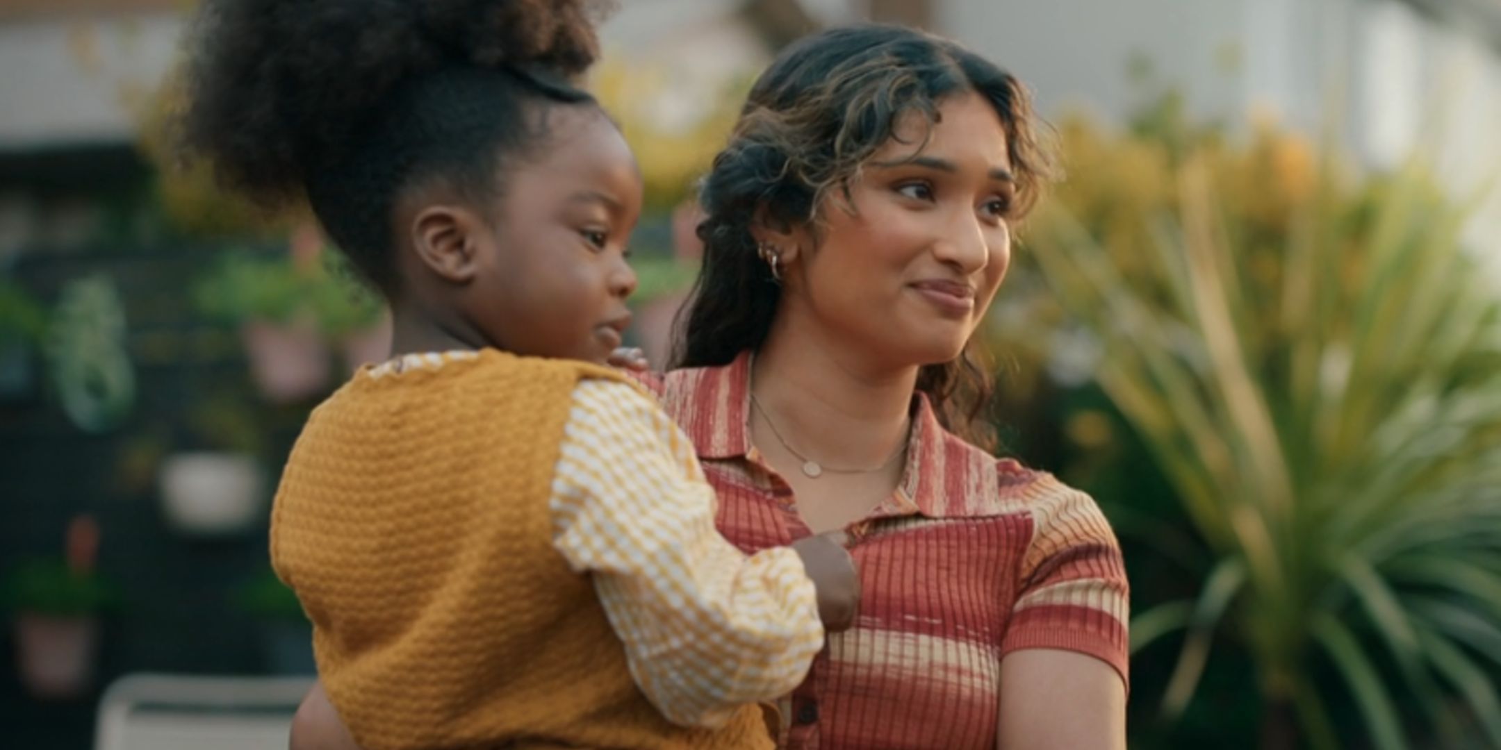 Varada Sethu como Belinda Chandra segurando Poppy em seu jardim, enquanto eles dizem adeus ao médico no episódio Doctor Who Season 15 "A guerra da realidade."