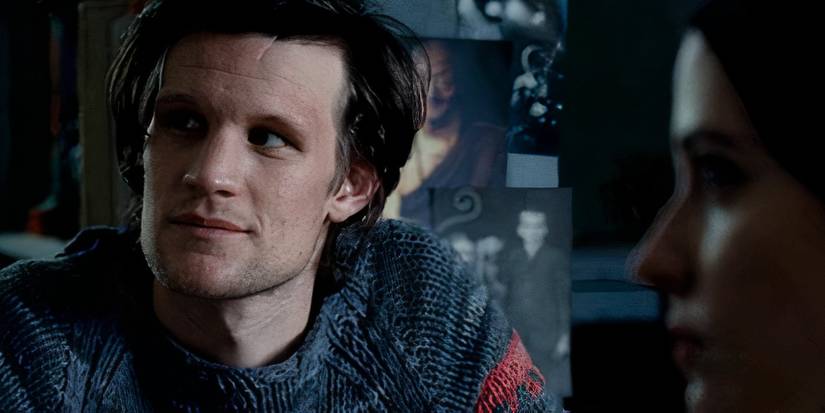 Matt Smith as Tommy staring off at something as Eva Green as Rebecca sits opposite him in Womb.