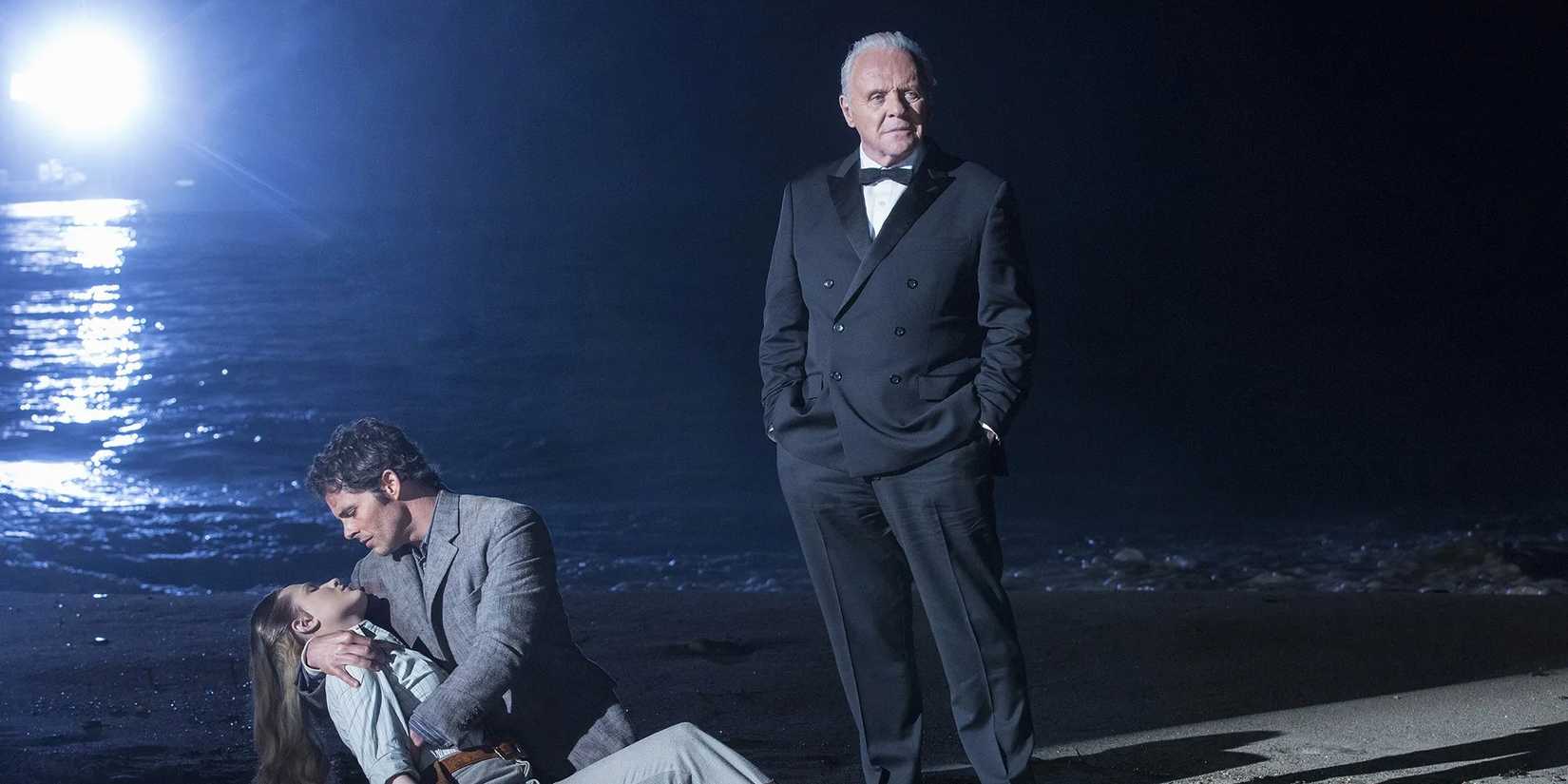 Robert Ford (Anthony Hopkins) standing on the beach in front of two hosts in Westworld.