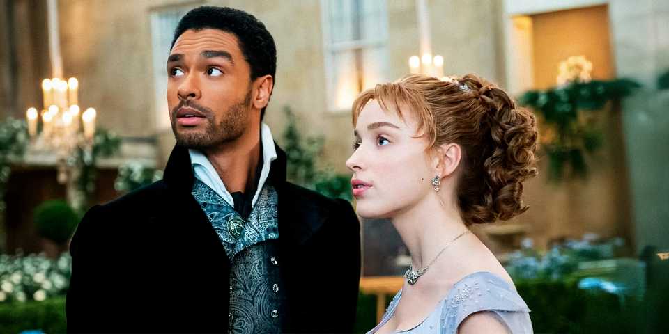 Rege Jean Pege and Phoebe Dynevor at a ball looking at something offscreen in Bridgerton