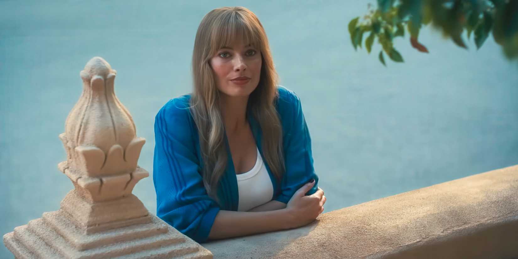 Margot Robbie leaning on a low wall in A Big Bold Beautiful Journey
