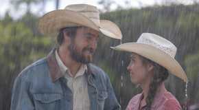 A man and woman smiling in the rain in Heartland
