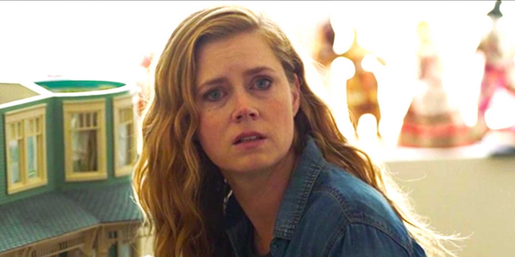 Amy Adams' Camille looks horrified beside a doll house in Sharp Objects