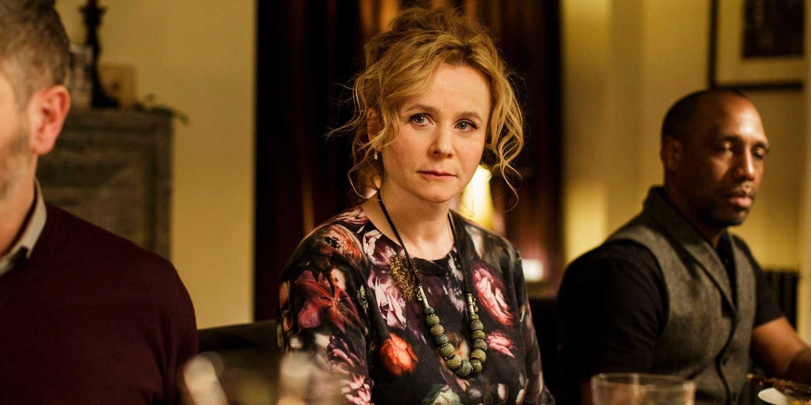 Emily Watson as Yvonne sitting at a dinner table among guests in Apple Tree Yard