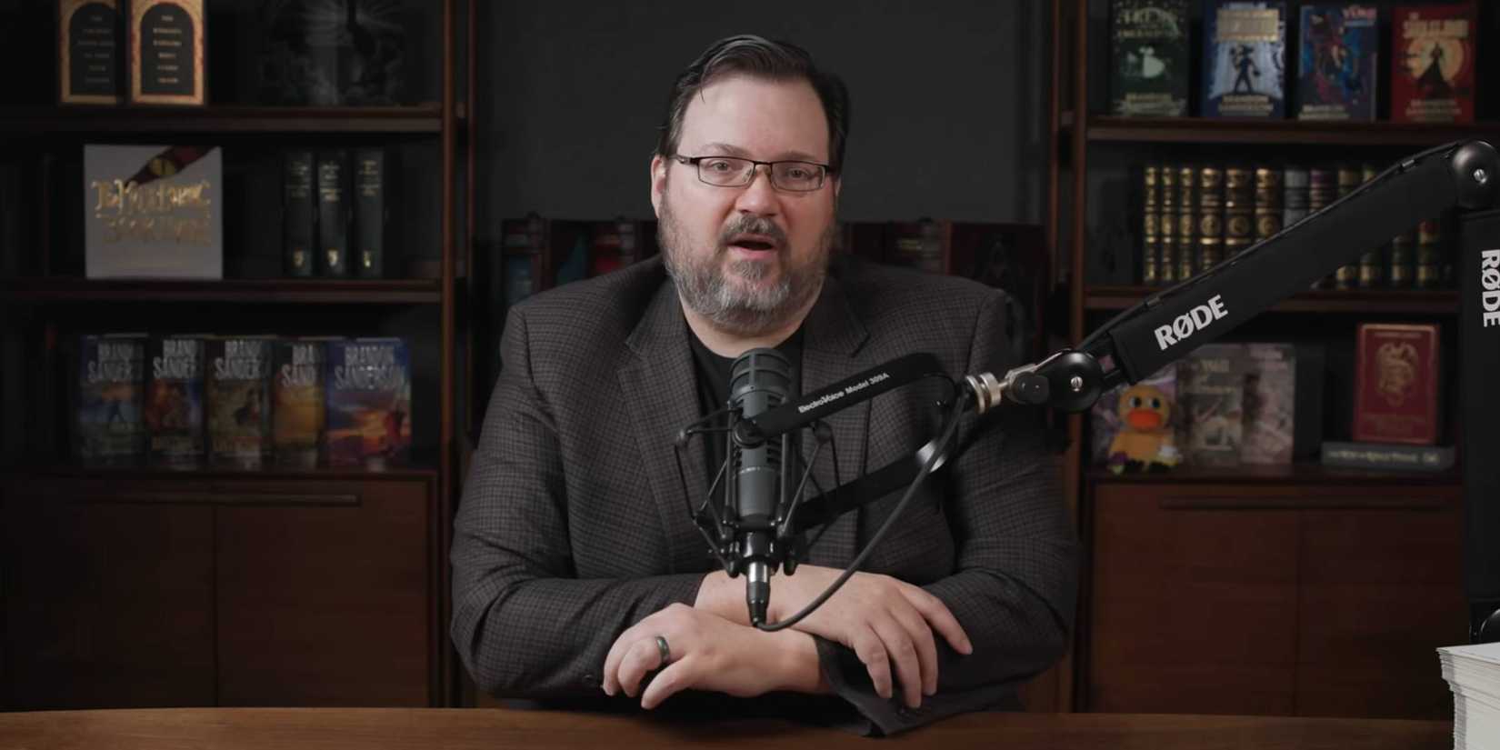Brandon Sanderson sitting in front of a microphone.