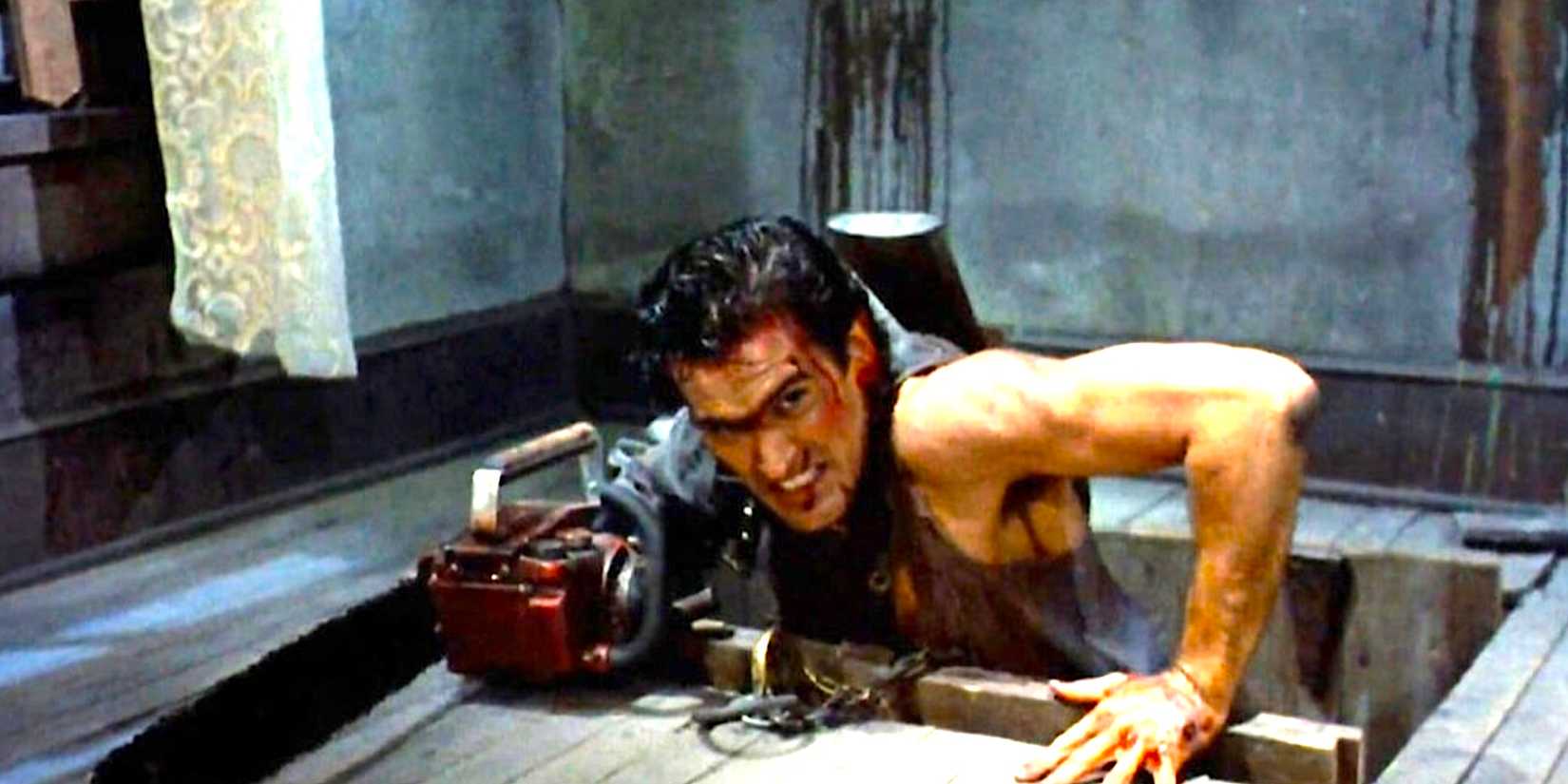 Bruce Campbell's Ash climbs out of a cellar with his chainsaw in Evil Dead 2