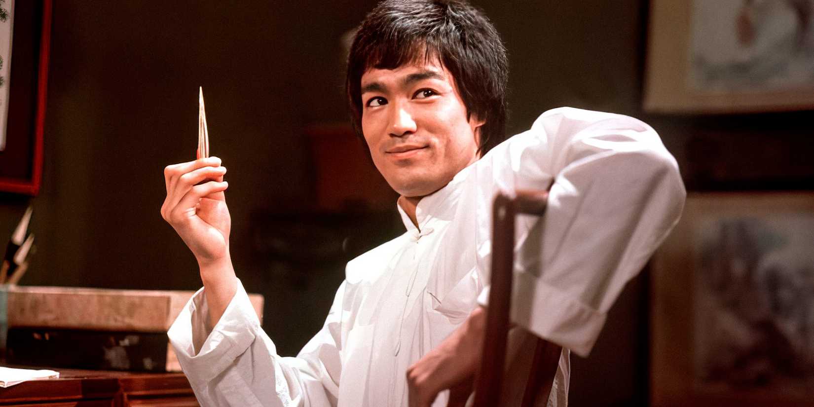 Bruce Lee sitting down and smiling in Enter the Dragon.