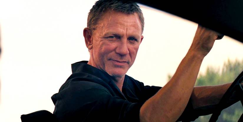 Daniel Craig as James Bond smiling at someone in No Time to Die