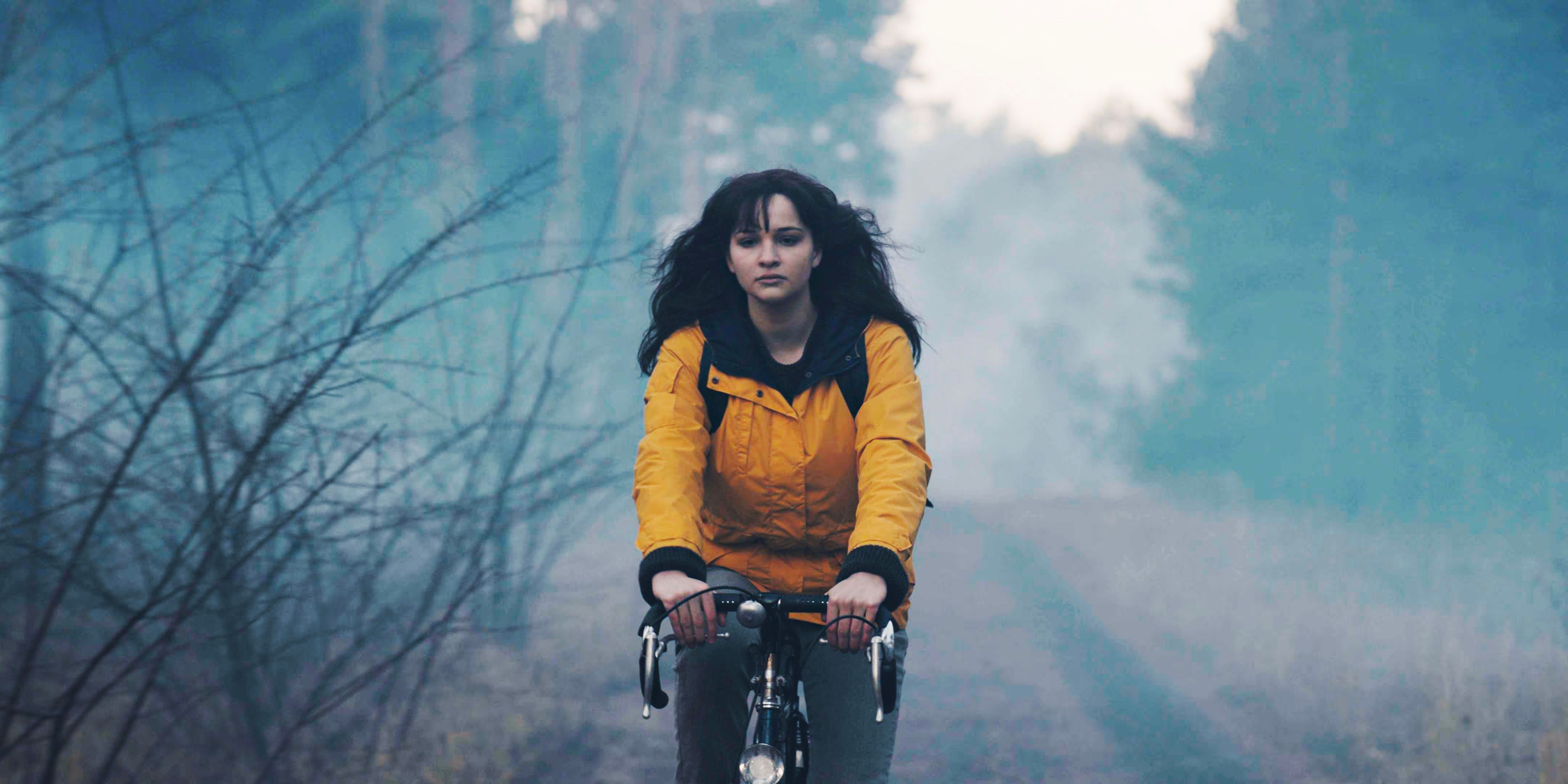 Dark Martha riding a bike and wearing the yellow raincoat