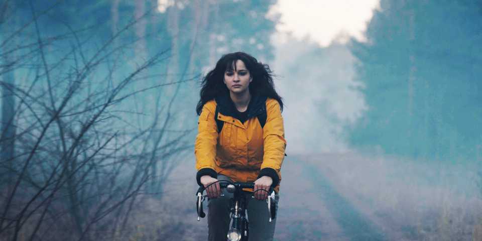 Dark Martha riding a bike and wearing the yellow raincoat