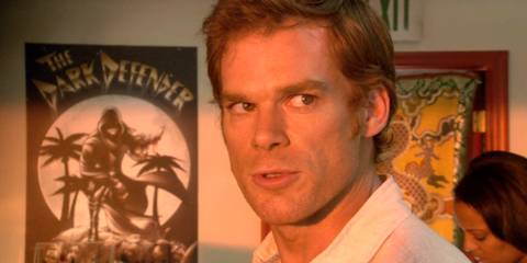 Dexter (Michael C. Hall) standing in front of a poster of the Dark Defender comic in Dexter season 2, episode 5
