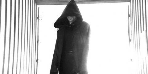 Dexter (Michael C. Hall) standing in a black cloak in a shipping container as the Dark Defender in Dexter season 2, episode 5