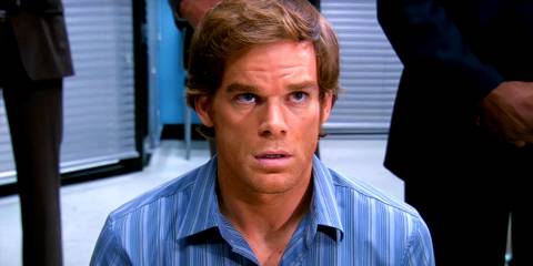 Dexter Morgan looking nervous staring up at a figure with people behind him in Dexter season 2