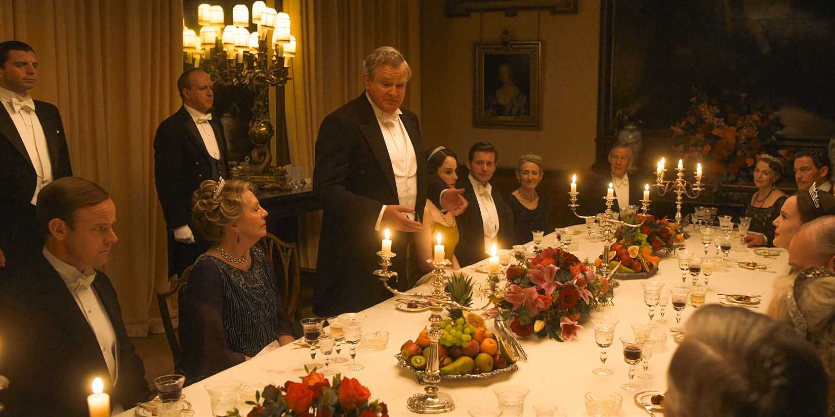 The cast seated around a large table in Downton Abbey: The Grand Finale