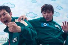 Gi-hun is excited while the Front Man holds him in Squid Game