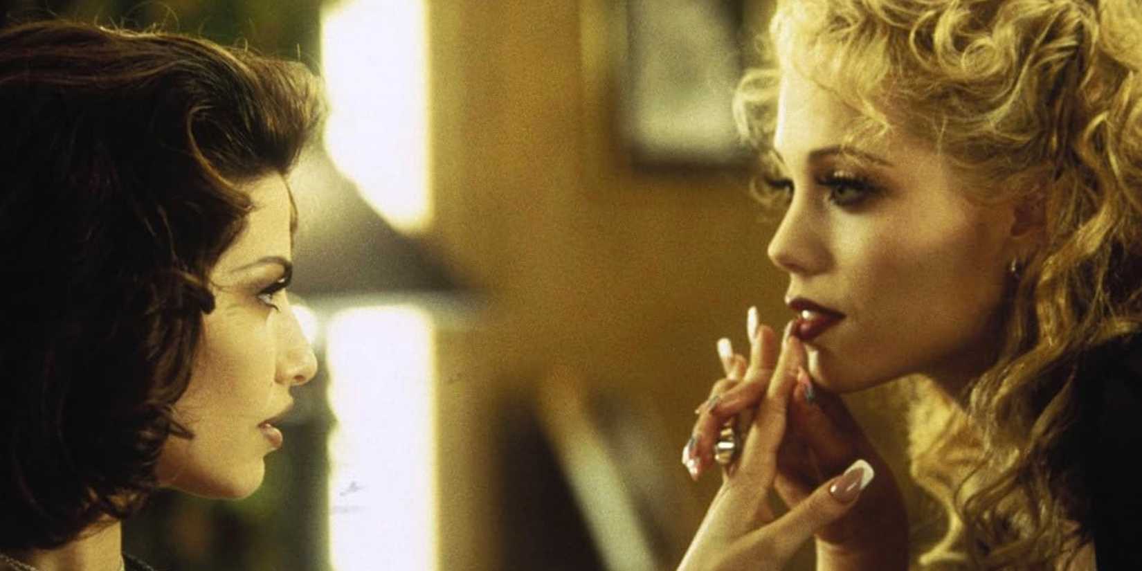 Gina Gershon and Elizabeth Berkley hold hands.