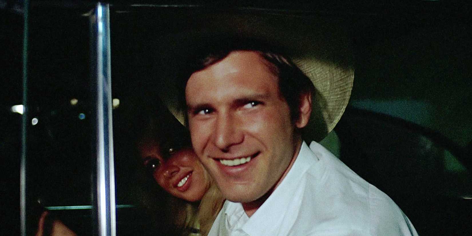 Harrison Ford smiles mischievously through a car window in a scene from American Graffiti