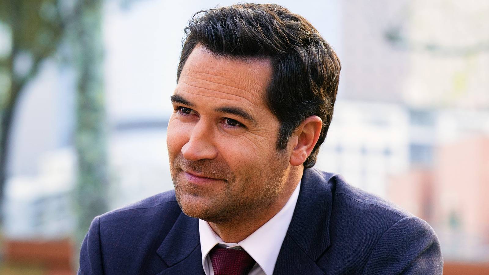 Manuel Garcia-Rulfo as Mickey Haller soft smiling at someone off-screen in The Lincoln Lawyer
