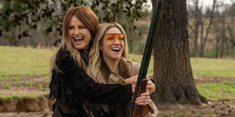 Margo hugs Sophie as she holds a gun in The Hunting Wives season 1