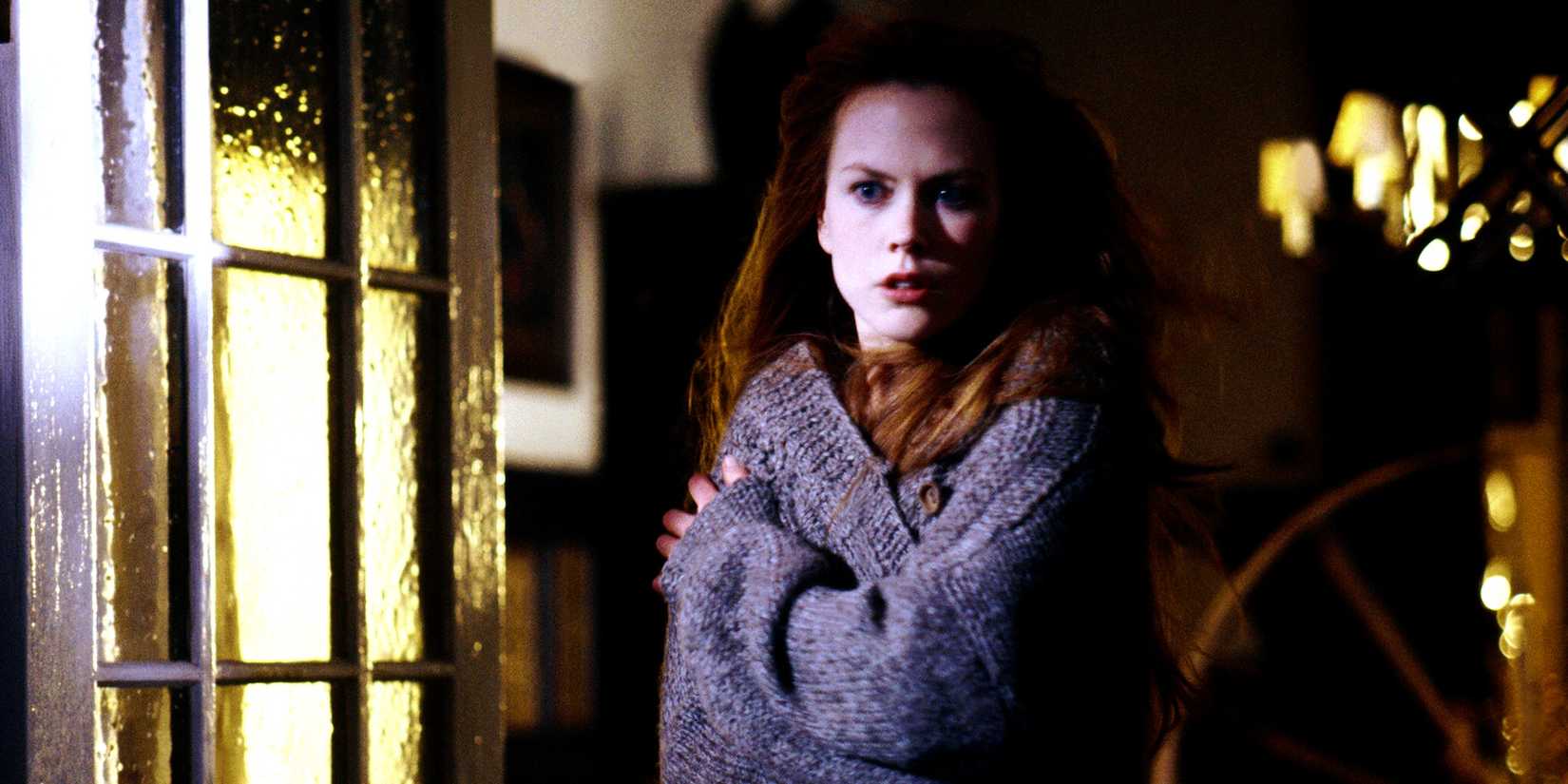 Nicole Kidman wrapped in a thick sweater staring outside in Practical Magic