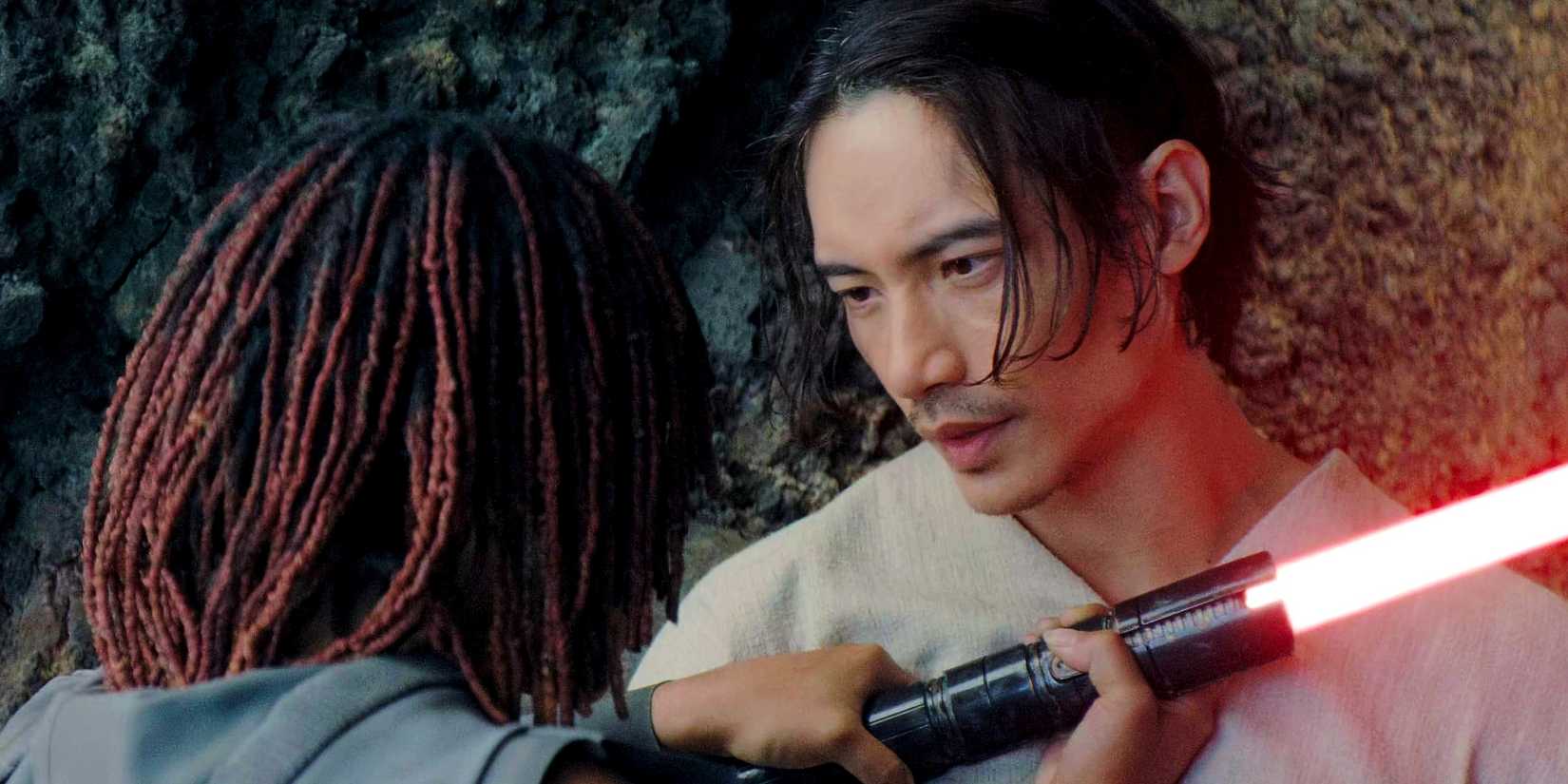 Osha holding a red lightsaber up to Qimir/the Stranger in The Acolyte