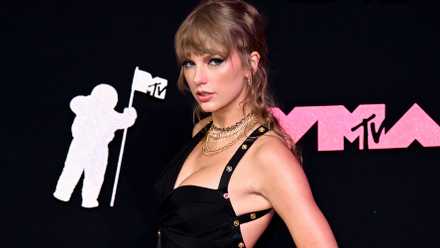 Taylor Swift poses on the red carpet in a black dress at the 2023 MTV VMA Awards.