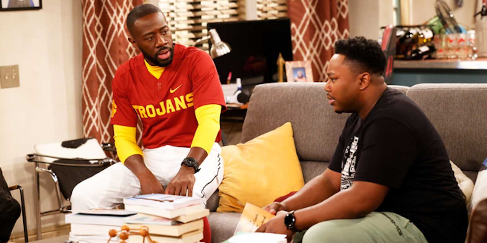 Malcolm e Marty sentados no sofá em The Neighborhood.