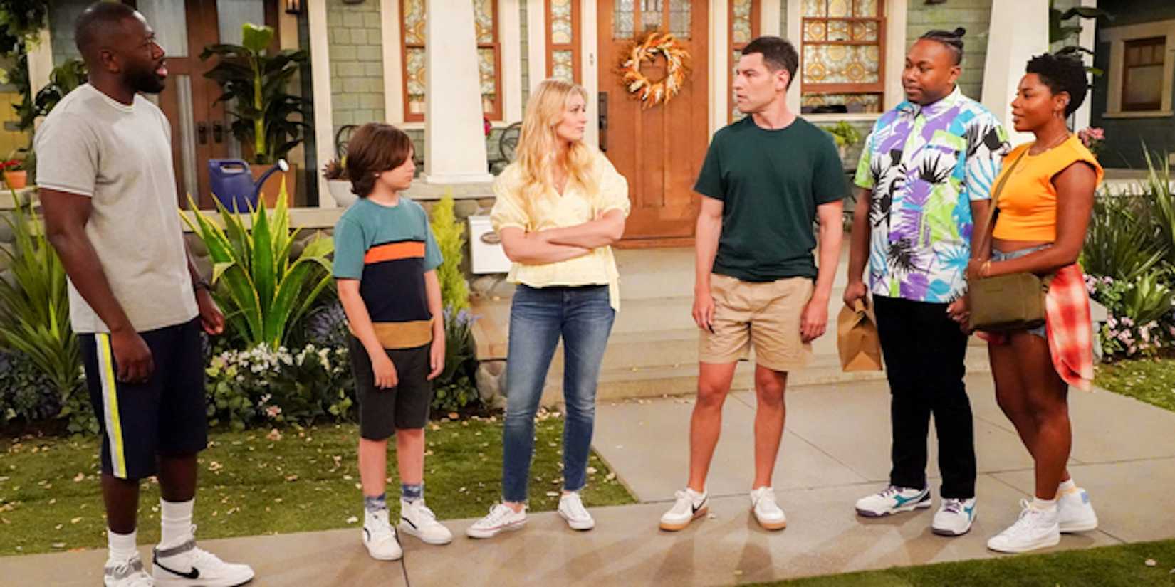 The main cast of The Neighborhood stand on a lawn in a row